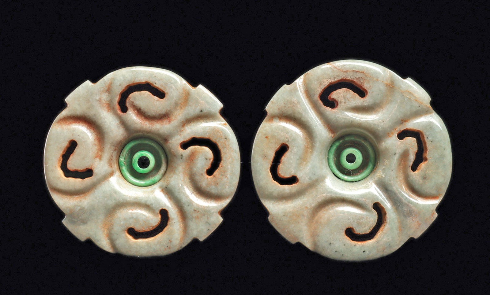 Maya Jade Earspools (2): Matching pair of carved creamy grayish-green jade floral ear ornaments, each having four openwork petals, set in the center with a carved brilliant blue-green jade concentric ring center piece. Both a
