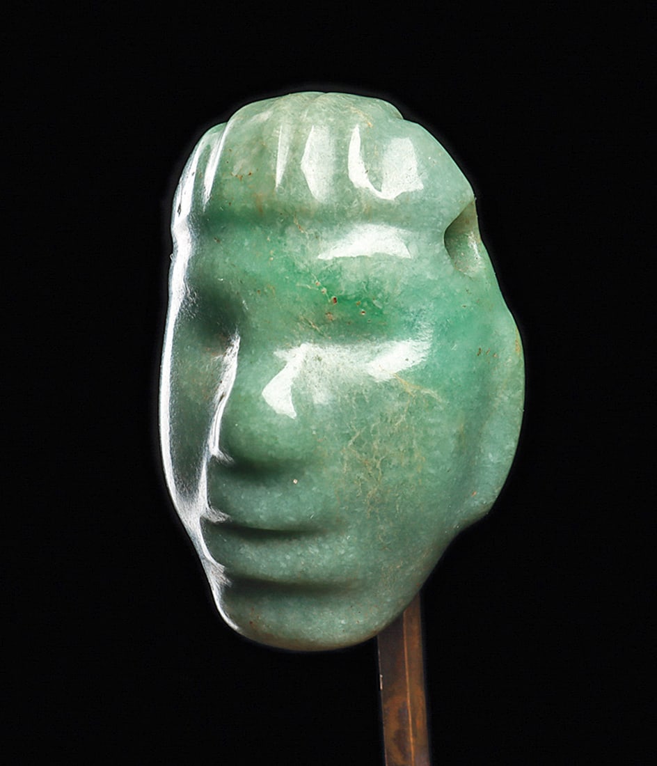 Maya Jade Head Pendant: Carved blue-green jade head pendant, depicted with a relief carved striated hairdo, and relief carved facial features, with a rounded nose, recessed eyes, parted lips, rounded chin and slim tab type e