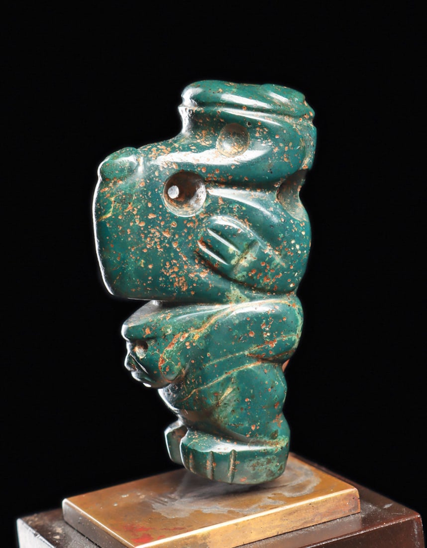 Costa Rican Blue Jade Composite Figure: Carved dark blue-green jade composite avian deity pendant having a large avian head with a long tapered hook beak, biconical drilled perforated eyes, slightly curved flat head cap with two large relie