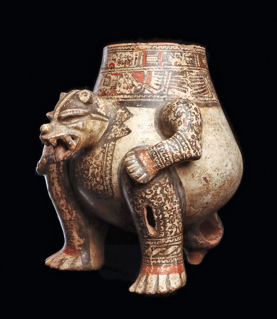 Nicoya Squatting Jaguar Polychrome Urn: Polychrome decorated pottery vessel in the form of a crouching jaguar with loop arms and paws resting on knees. Open toothy mouth with a rattle ball in his mouth, openwork tail support, rattles incorp