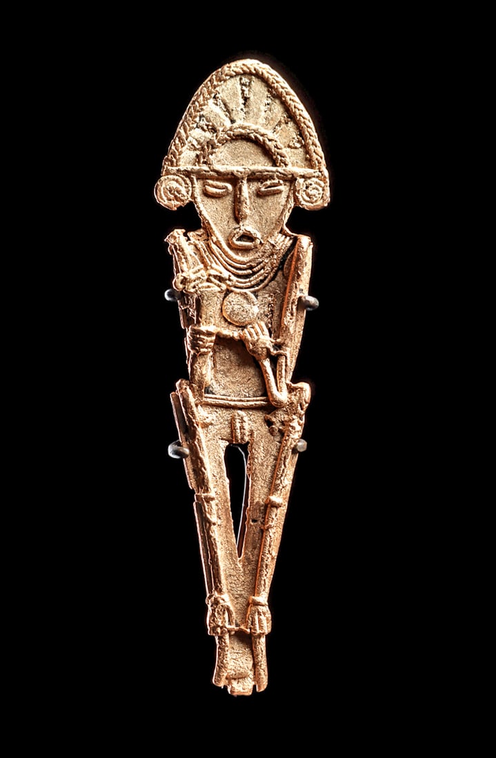 Muisca Gold Tunjo Figure: Cast gold votive plaque depicting a standing male figure holding long implements, probably an atl-atl and a serpent headed scepter. Wearing a multistrand necklace, a tall domed crown, and spiral earri
