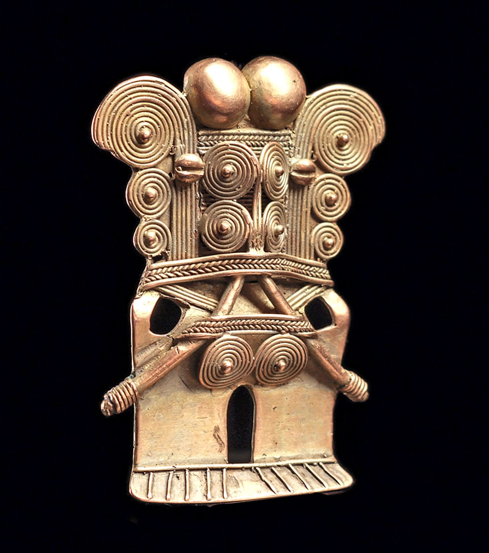 Tairona Gold Stylized Deity Pendant: Classical type, cast gold pendant of stylized human form playing a double dube flute. Decorated with multiple spiral elements and two balls at the top, each housing a suspension loop behind, one missi