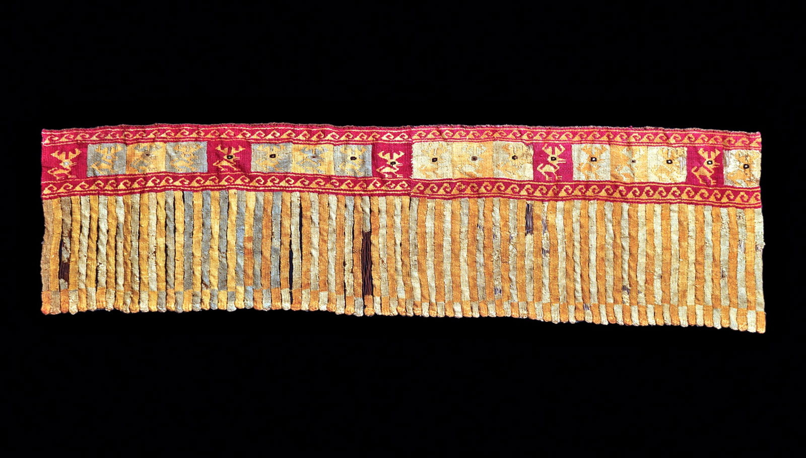 Chancay Fringed Border Depicting Deer Inscribed in Squa: A section of a long fringed border, having an upper border composed of alternating box registers, each containing a deer with large antlers. Upper and lower wave pattern borders. Three losses in the b
