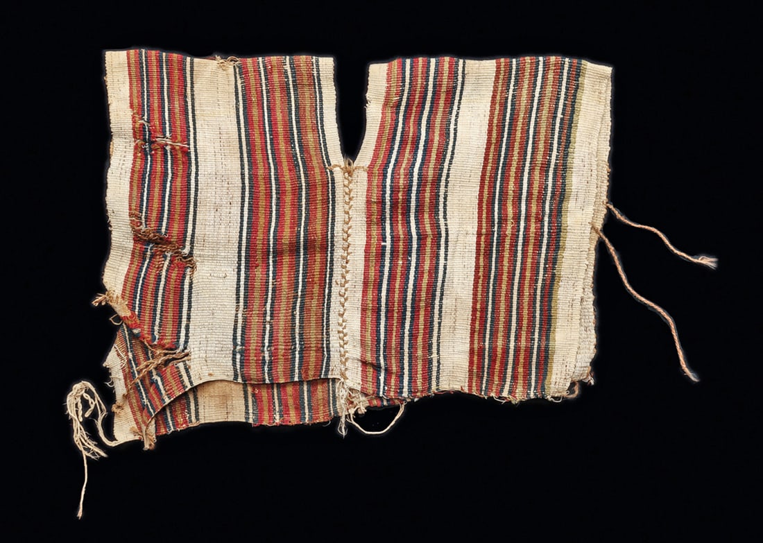 Inca Child's Shirt: Woven camelid wool textile child's shirt, having an overall vertical striped pattern. Some scattered light staining and one side edge quite tattered. 7"W. x 12"L. Provenance: Collection of Laurence a