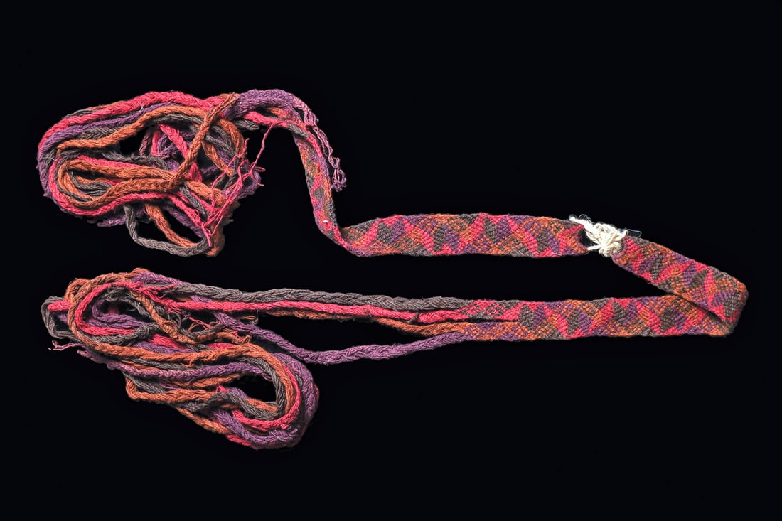 Chiribaya Decorated Sash: Long woven and braided textile and string sash or wrap with with geometric pattern belt ends. Some tattering and breaks to the string ropes. The Chiribayan group came to be after the collapse of the T