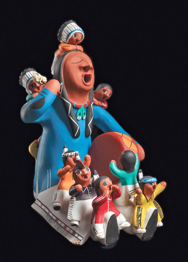 Native American Dancers / Family Scene: Large plaster dance group figural sculpture depicting a seated drummer, playing the drum and singing, surrounded by ten small children wearing various multicolor painted costumes, all singing, two wea