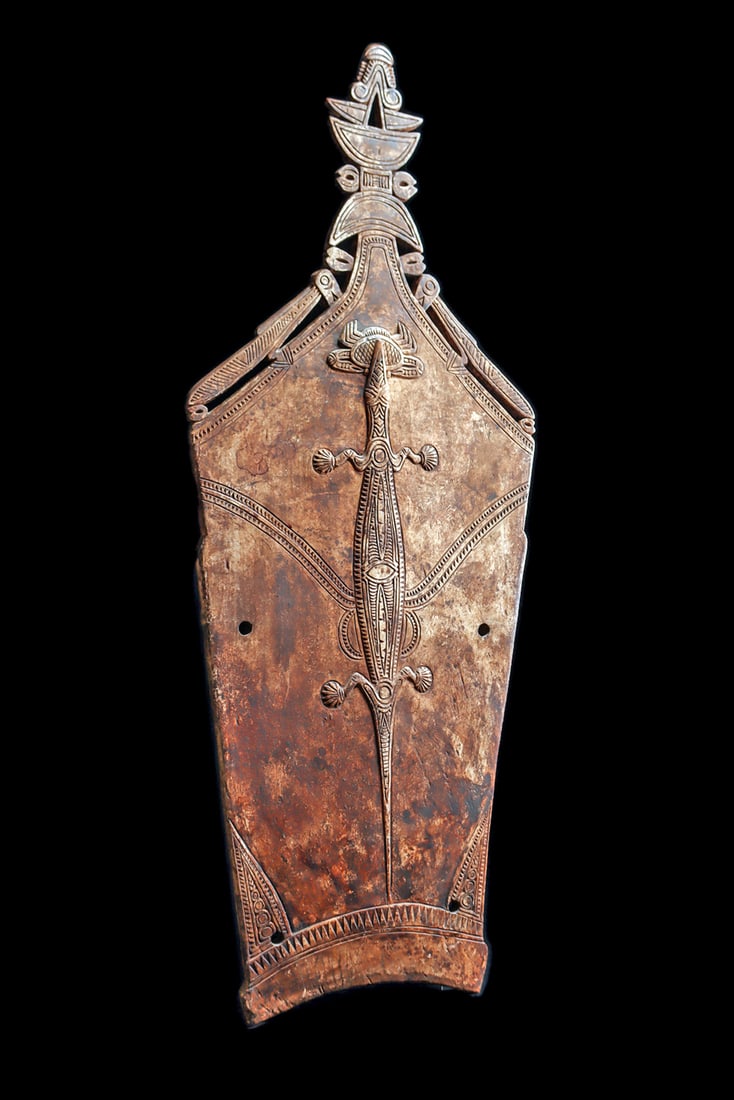 Huon Gulf Splashboard: Large carved heavy hardwood splash board known as a "damundam"carved with a large relief sea crocodile in the center with a crab in its mouth, linear patterns engraved on body. The top edge of the boa