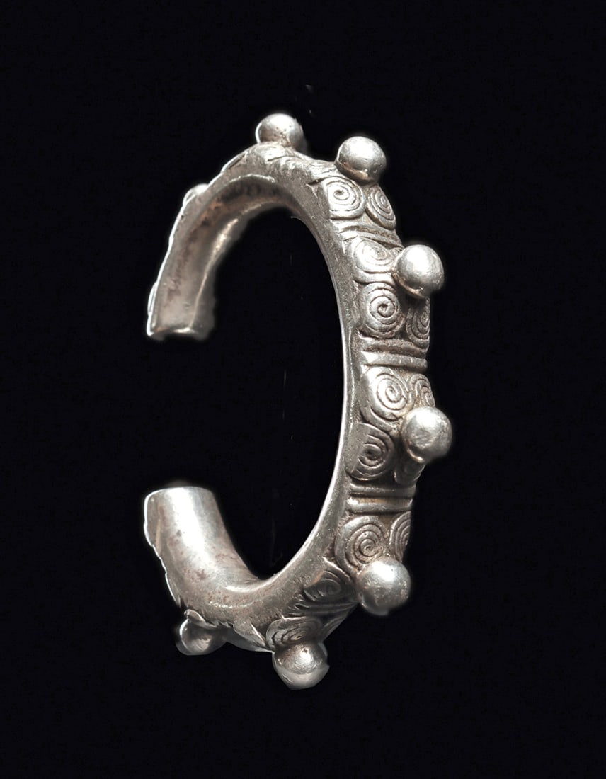 Timor Silver Cuff: Cast solid silver cuff bracelet, decorated in high relief with ten registers, each consisting of a prominent center ball surrounded with four scroliate elements. Good black patina in the low areas. In