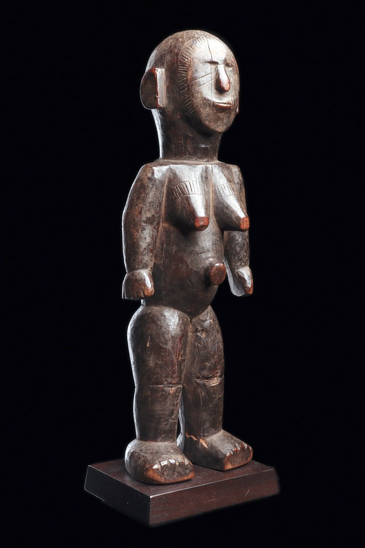 Mossi Female Figure: Robust standing female figure carved from dense hardwood, her rounded form accented with lightly notched lines framing the face and scarification marks along the cheeks and above the breasts. Rich, de