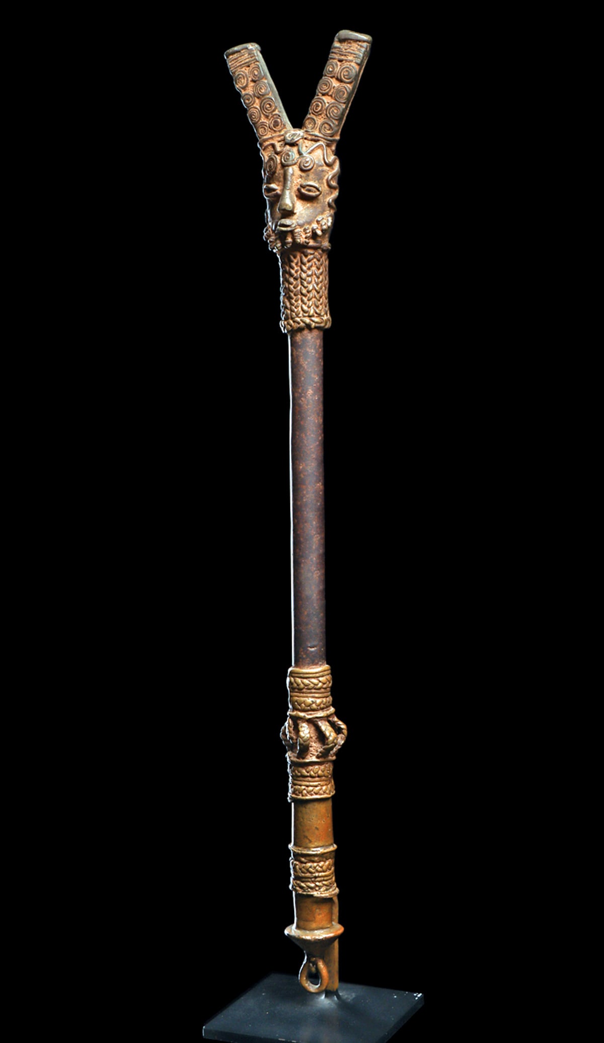 Yoruba Ogboni Bronze Sceptre: Heavy and intricately detailed iron and brass alloy staff with a Janus head finial with double pronged tall headdress. One face with coiled beard and opposing face with braided band across forehead an