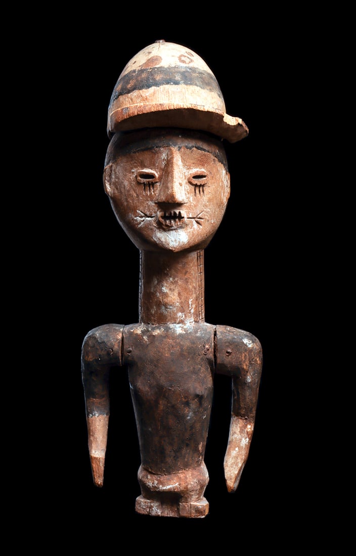 Figure of Child with Removable Hat: Carved wood figure of boy with separately carved cap attached to top of head with iron alloy pin, face carved with slit eyes and mouth, scarification on face and neck, long arms attached with nails, a