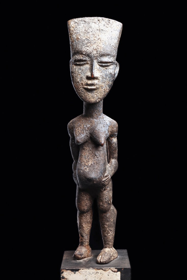 Ashanti Standing Pregnant Female: Finely carved pregnant female figure distinguished by a tapered, trapezoidal forehead and a delicately modeled, naturalistic face. She stands with her hands resting beside her swollen abdomen, bearing