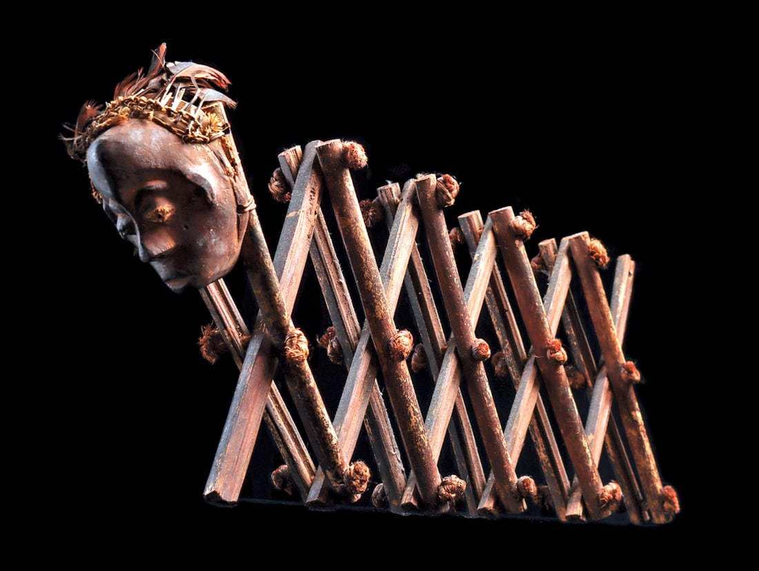 Pende Divination Implement: Oracle tool, "galukoji" with a carved wood anthropomorphic mask woven with a fiber headband of feathers, slightly upturned nose with hollow nostrils, concavities in cheeks, beneath bulging eyes. The e