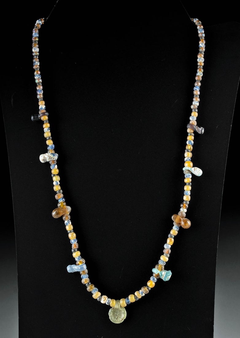 Ancient Roman-Byzantine Multicolor Glass Bead Necklace: Roman, Imperial Period to Byzantine Periods, ca. 1st to 7th century CE. A vibrant necklace composed of ancient glass beads of varying hues, including amber, cobalt, honey-yellow, turquoise, and pale g