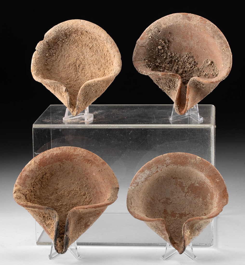 Four Ancient Levantine Shell Form Pottery Oil Lamps: Near East, Holy Land / Levant, Late Bronze Age to Iron Age, ca. 1550 to 200 BCE. A group of four pottery oil lamps, each formed in a shell-shaped design with shallow, flared bodies and pinched spouts