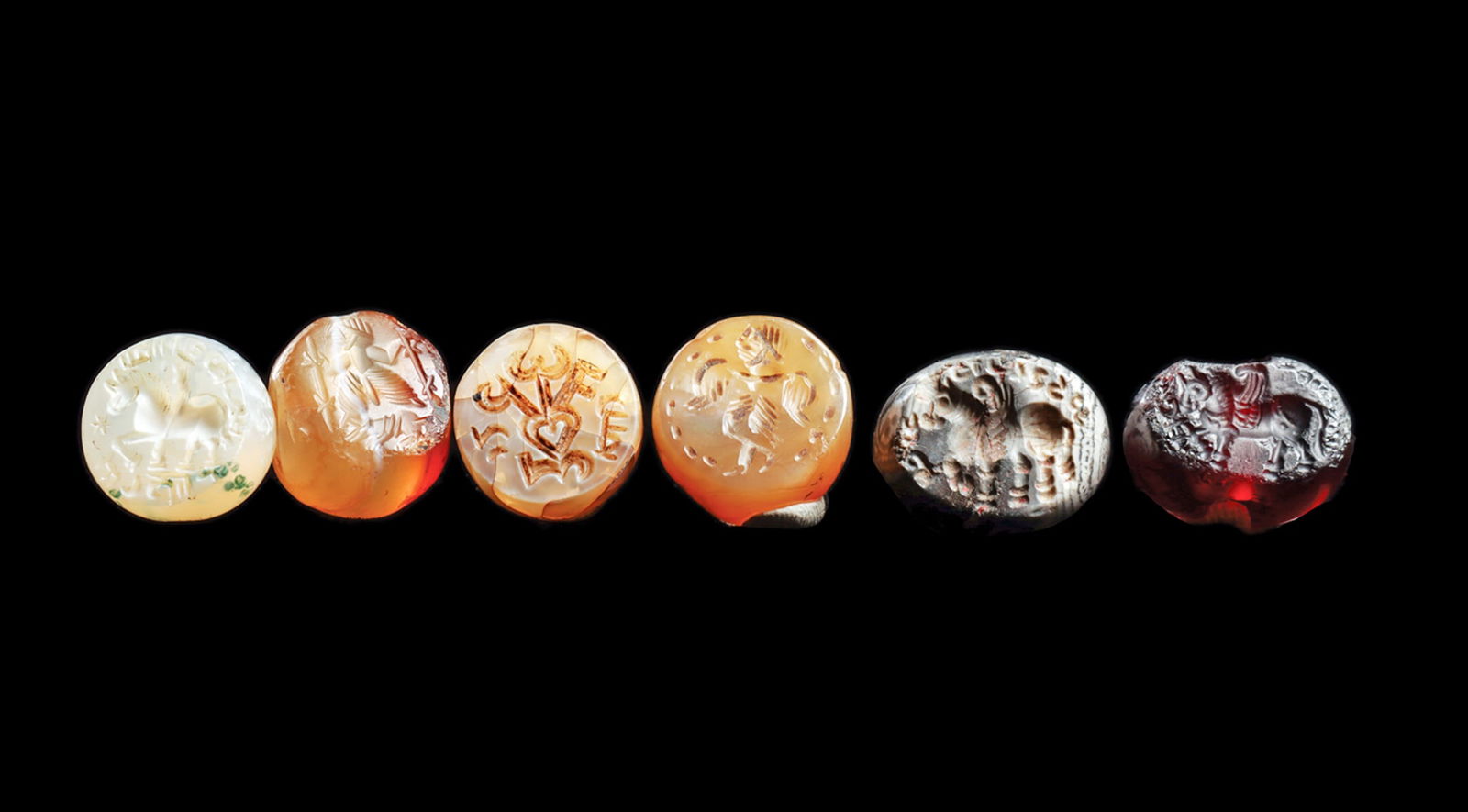 Sasanian Stamp Seals (6): Six different carved stamp seals including four carved agate seals, a deep red glass seal and a gray and white banded agate example. All with carved impressions including: three similar winged horses