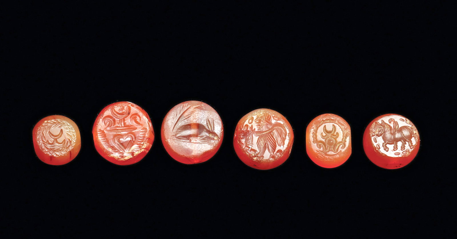 Sasanian Carnelian Stamp Seals (6): Group of six orange carnelian stamp seals, all having a drilled suspension hole through their centers, and carved with a stamp impression including: a winged figure having some edge roughness, a rabbi