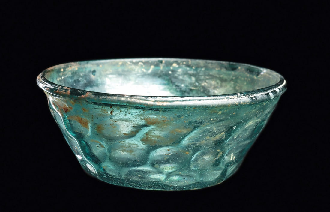 Islamic Bowl with Expanded Ovoid Pattern: Blown rich blue-green glass bowl having tapered wall and a rolled rim. Pattern molded with an expanded ovoid design. Some scattered areas of surface deposits and iridescent patina. Intact, exc. cond.