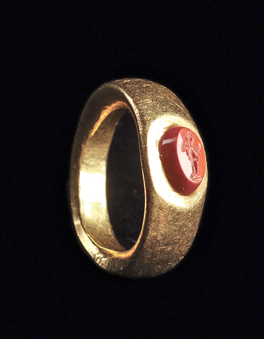 Roman Gold Finger Ring: Gold finger ring having a wide slightly tapered band, with a flat ovoid bezel, set with a red jasper oval tapered intaglio engraved with a stylized figure of Athena. Intact, exc. cond. Sturdy and suit