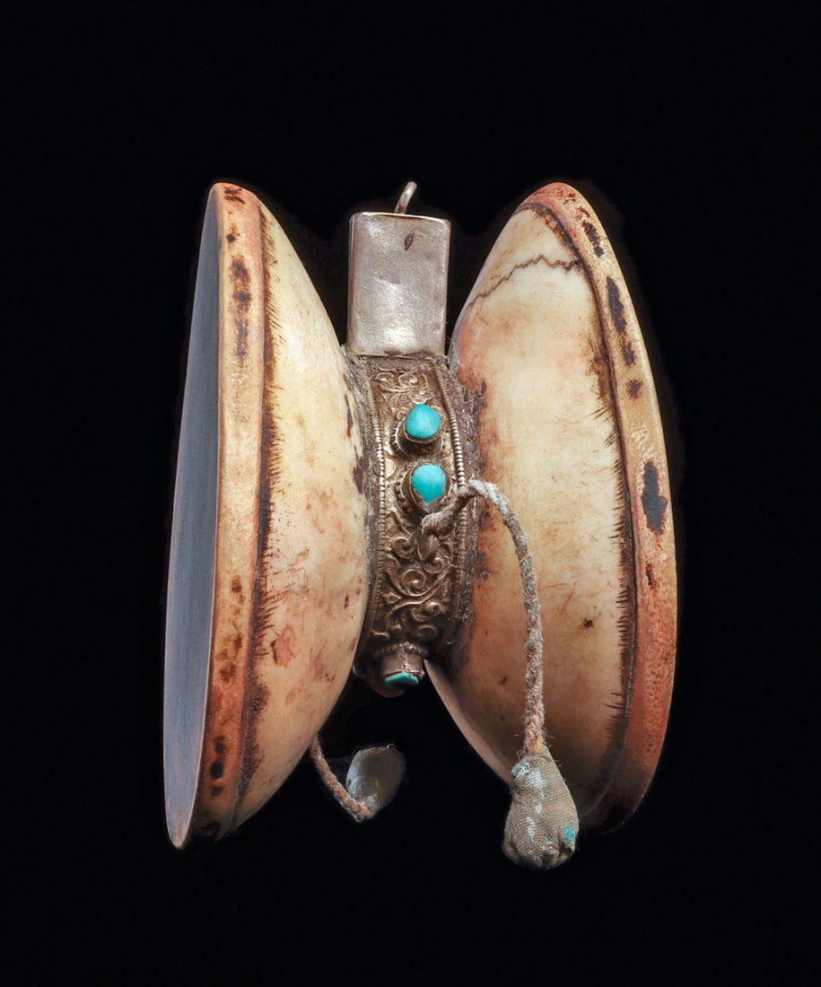 Tibetan Double Skull Drum: Small skull drum made from two crania that are connected at the crowns. The crania are covered with dyed brown skins, stretched to create the drum surface. The joint is covered with a silver collar de