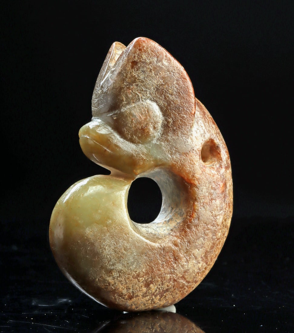 Chinese Hongshan Nephrite Jade Pig Dragon Pendant: China. Hongshan Culture, Neolithic Period, ca. 4700-2900 BCE. A carved nephrite jade pendant depicting a stylized pig-dragon (zhulong), formed as a thick, curled openwork arc with a pronounced head, r