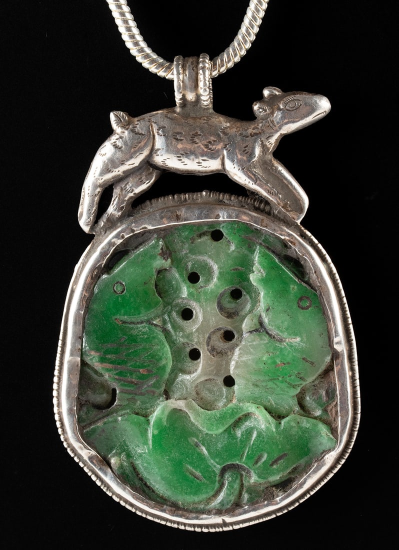 Chinese Sterling Silver & Greenstone Animal Pendant: East Asia, China / Tibet, ca. early to mid-20th century CE. A sterling silver pendant set with a carved green stone plaque depicting the Buddhist auspicious pair of fish rising from a lotus in low rel
