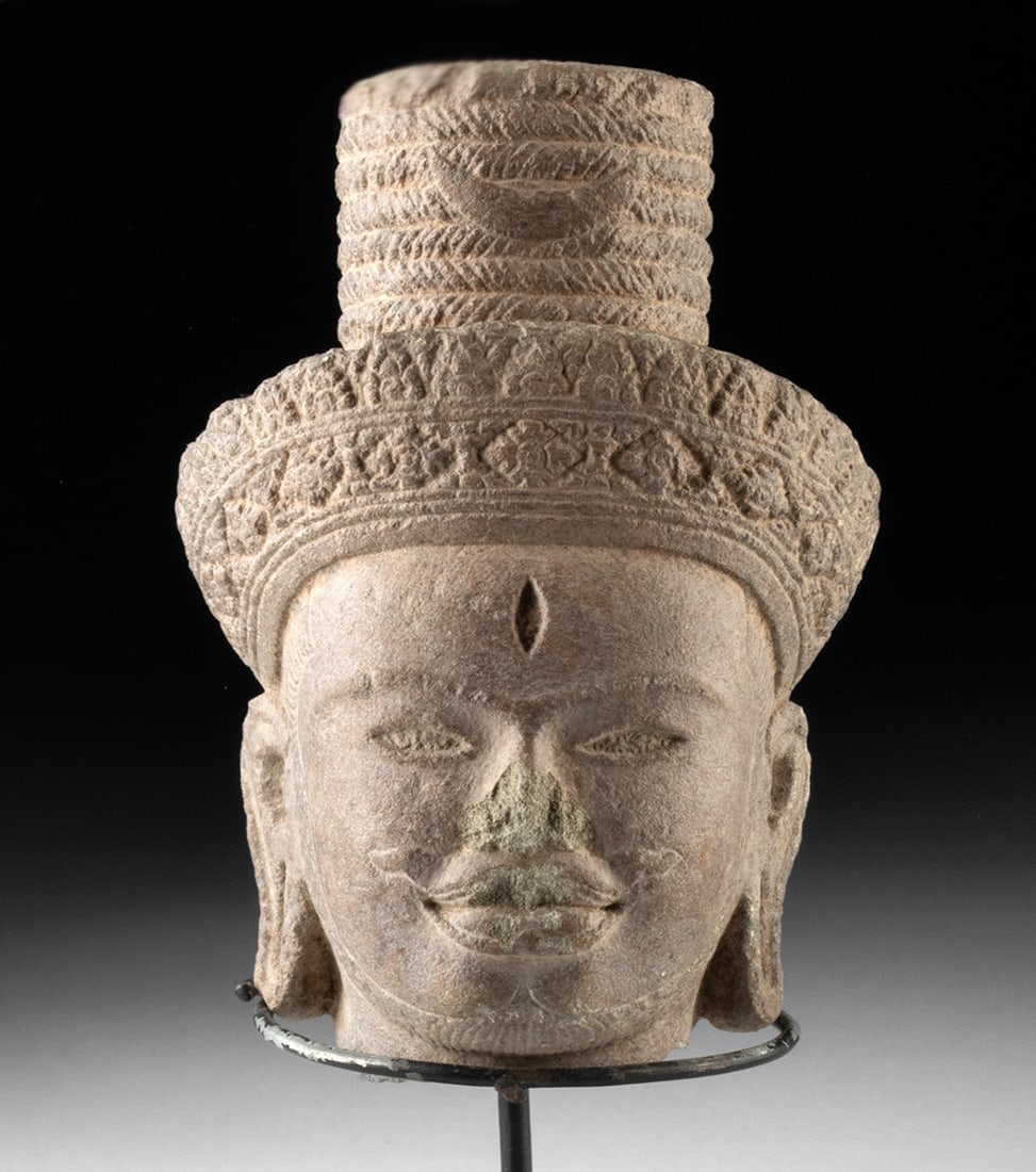 Khmer Angkor Red Sandstone Head of Shiva: Southeast Asia, Cambodia, Khmer (Angkor), ca. 12th to 13th century CE. A red sandstone head from a temple sculpture depicting Shiva, shown with elongated earlobes that convey divine and royal status i