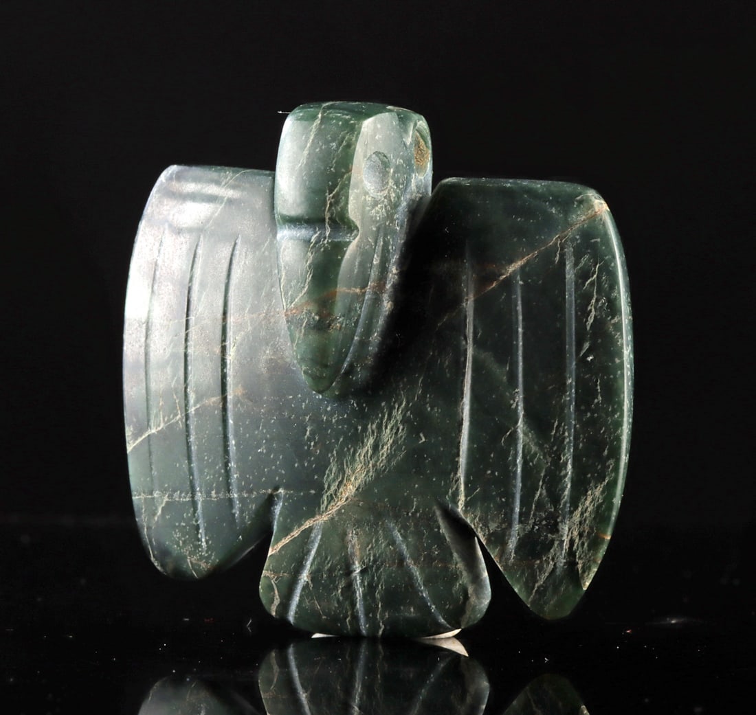 Chinese Qing Greenstone Bird Pendant: East Asia, China, Qing Dynasty, ca. 19th century CE. A carved greenstone pendant in the form of a stylized bird, rendered in a manner inspired by much earlier Neolithic jade traditions. The figure dis