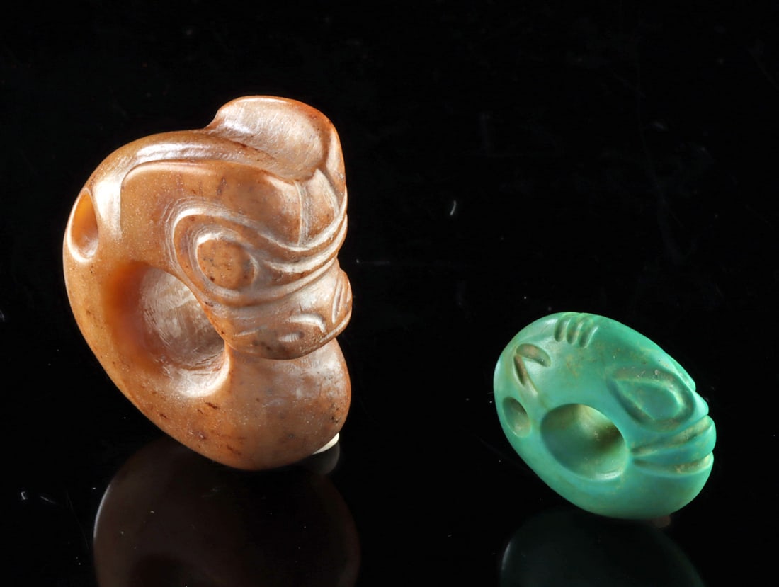 Chinese Stone Pig Dragon & Carved Bead Pendant: East Asia, China, ca. 20th century CE. A carved stone pig-dragon pendant with circular body and stylized head, accompanied by a small turquoise hued magnesite bead carved with simple facial features a