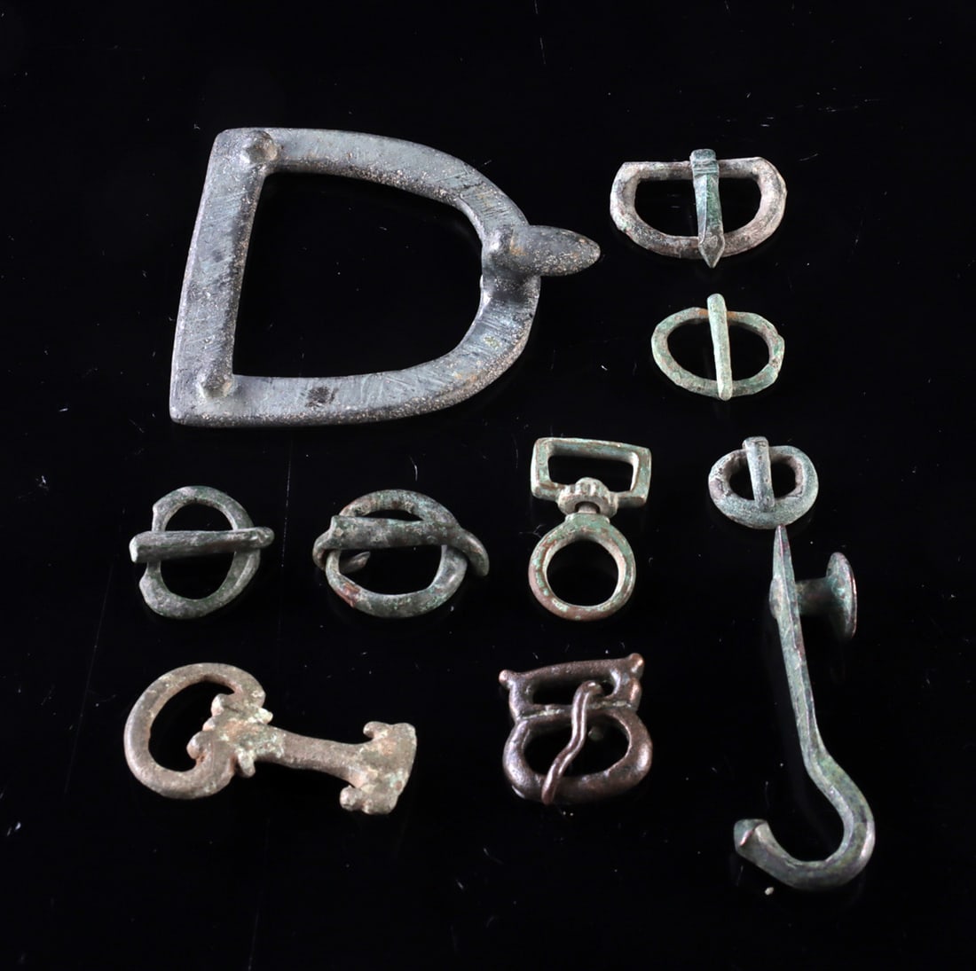 10 Roman Bronze Belt Buckles, Clasps & Attachments: Roman, Imperial period, ca. 1st to 3rd century CE. A varied group of ten Roman belt components including buckles, clasps, attachment fittings, and a decorative hook, cast in bronze and related copper