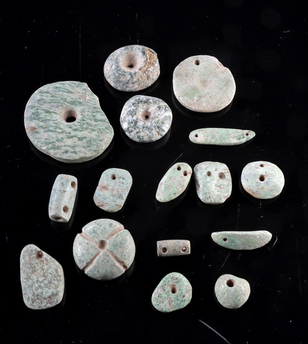 Ancient Mesoamerican Jade & Greenstone Beads, 16 pcs: Pre-Columbian, Mexico to Guatemala, Olmec, Mezcala to Maya, ca. 500 BCE to 900 CE. A collection of ancient greenstone and jade beads in varied shapes including discs, elongated forms, and drilled pend