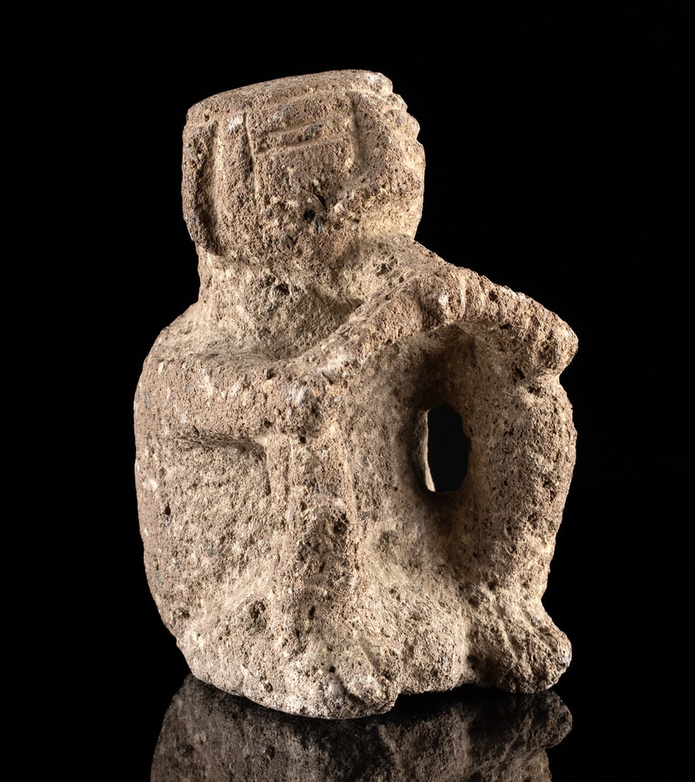 Pre-Columbian Costa Rican Volcanic Stone Seated Figure: Pre-Columbian, Costa Rica, Atlantic Watershed, ca. 800 to 1200 CE. A seated volcanic stone figure holding a flute or perhaps other implement to his mouth. Size: 2.5" L x 2" W x 3.25" H (6.4 cm x 5.1