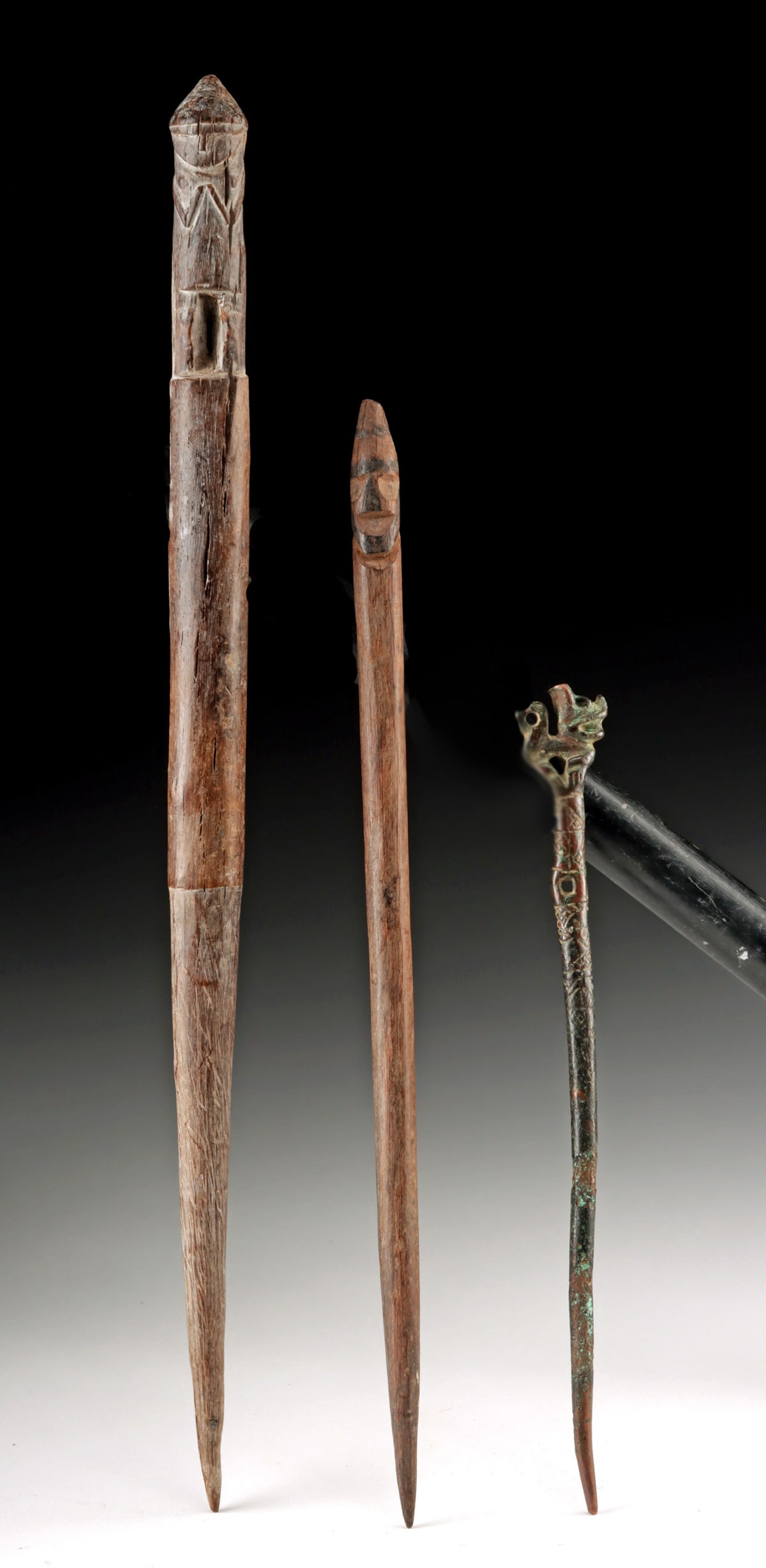 Three Chimu Wood Bobbins & Copper Tupu Pin w/ Feline: Pre-Columbian, Peru, North Coast, Chimu Culture, ca. 900 to 1470 CE. A group of a tupu cast in copper and two weaving bobbins carved from wood. The copper example features an incised shaft with