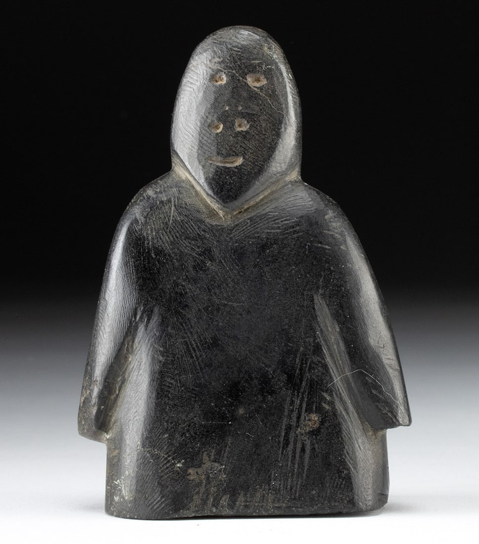 Inuit Soapstone Figural Carving, Signed in Inuktitut: First Nations, Canada, northwestern Quebec, ca. mid to late 20th century CE. A hand-carved soapstone figure with a compact, simplified form and a thick torso, with arms held close to the sides. The su
