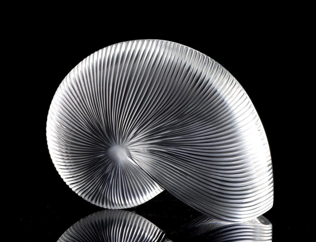 French Baccarat Crystal Nautilus Shell Sculpture: Western Europe, France, ca. late 20th century CE. A clear crystal glass nautilus shell sculpture formed with fine radiating ribs that spiral inward toward a frosted central core, creating striking opt