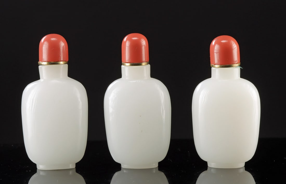 Three Matching Chinese Opaque White Glass Snuff Bottles: East Asia, China, late Qing to Republic era, ca. early to mid-20th century CE. A set of three matching opaque white glass snuff bottles of rounded form, each fitted with a coral-colored stopper mounte