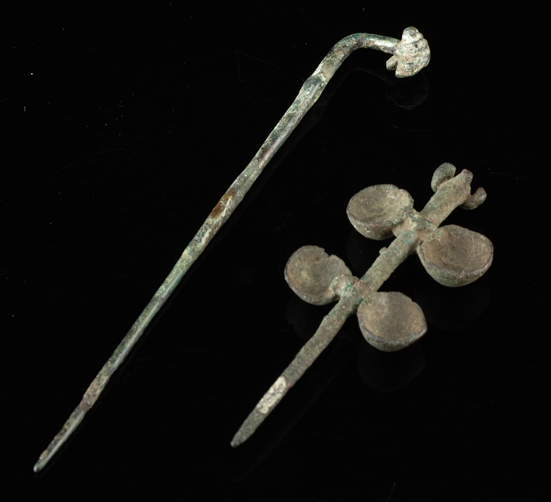 Pair of Luristan Bronze Fibulae - Ram Head Finials: Ancient Near East, Luristan, Early Iron Age, ca. 1000 to 700 BCE. A pair of slender bronze fibulae that turn everyday fastening into a small act of devotion, each crowned with a stylized ram's head po