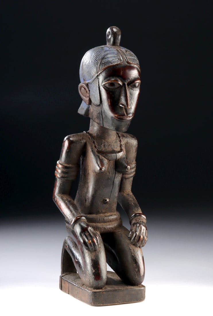 Rare Nigerian Eloyi Wood Kneeling Female Figure: West Africa, Nigeria, possibly Afo or related regional tradition, ca. 20th century. A carved wooden kneeling female figure with an enlarged head and elongated facial planes, shown with hands resting
