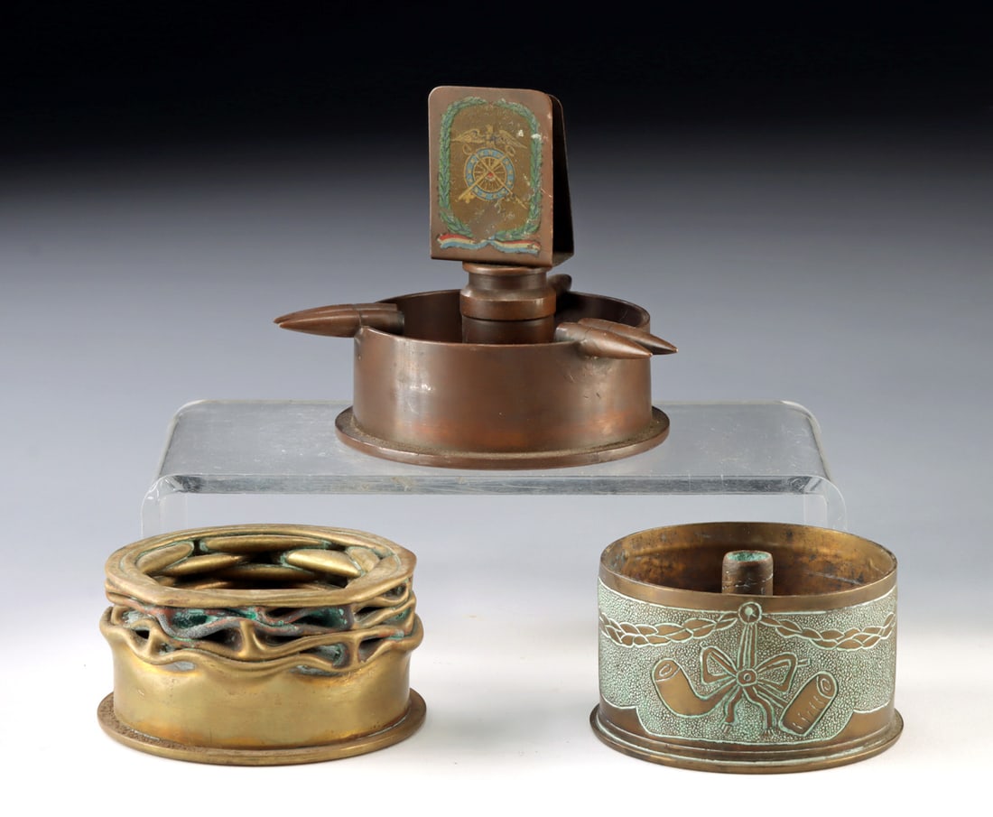 WWI & WWII Trench Art Ashtray Group, 3 pcs: Europe and United States military, World War I and World War II periods, ca. early to mid-20th century CE. A compelling group of three trench art ashtrays fashioned from spent military materials, each