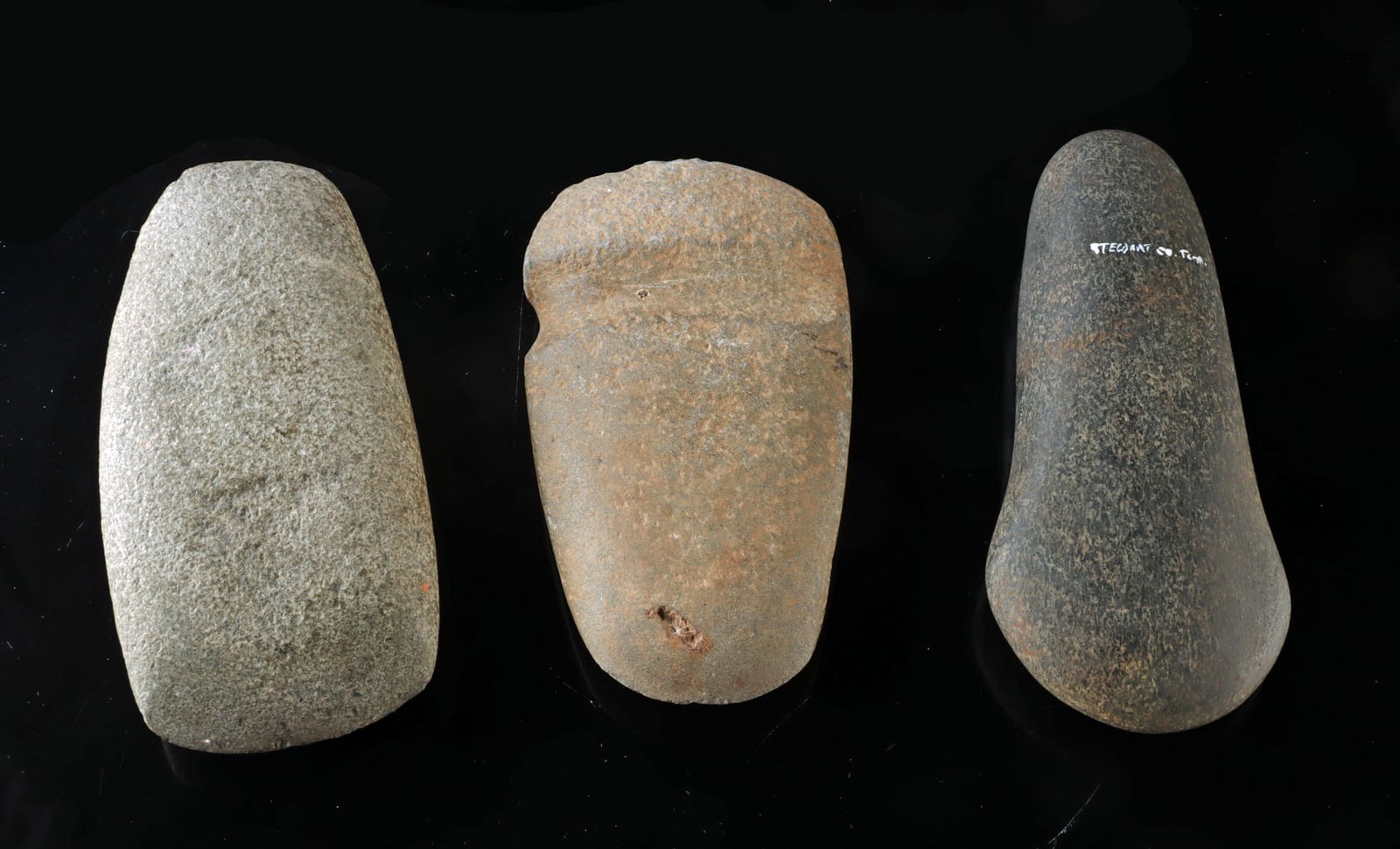Woodland Period Stone Axe Heads - Group of 3: Native American, Eastern Woodlands, Woodland period, ca. 1000 BCE to 1000 CE. A group of three Native American stone axe heads including one light gray example with a 3/4 groove and two ungrooved or c