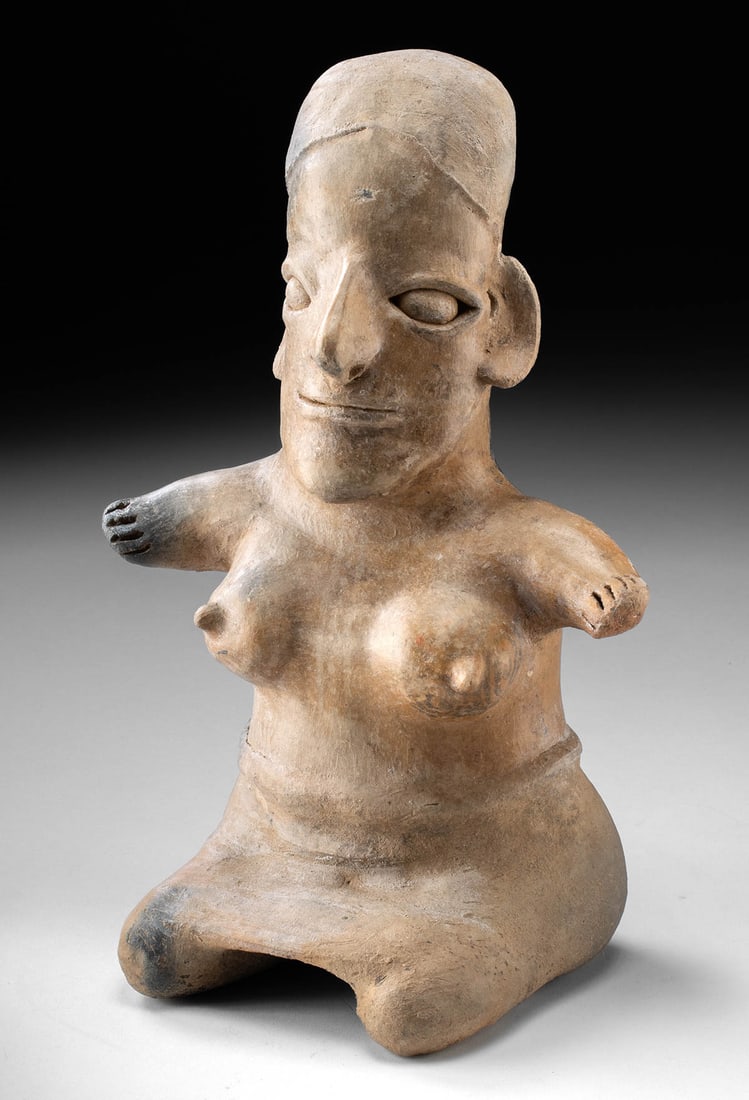 Jalisco Seated Semi-Nude Female Pottery Figure: Pre-Columbian, West Mexico, Jalisco, ca. 300 BCE to 300 CE. A distinctive ceramic figure of a seated female presents the bold, hieratic style characteristic of the Jalisco sculptural tradition. The