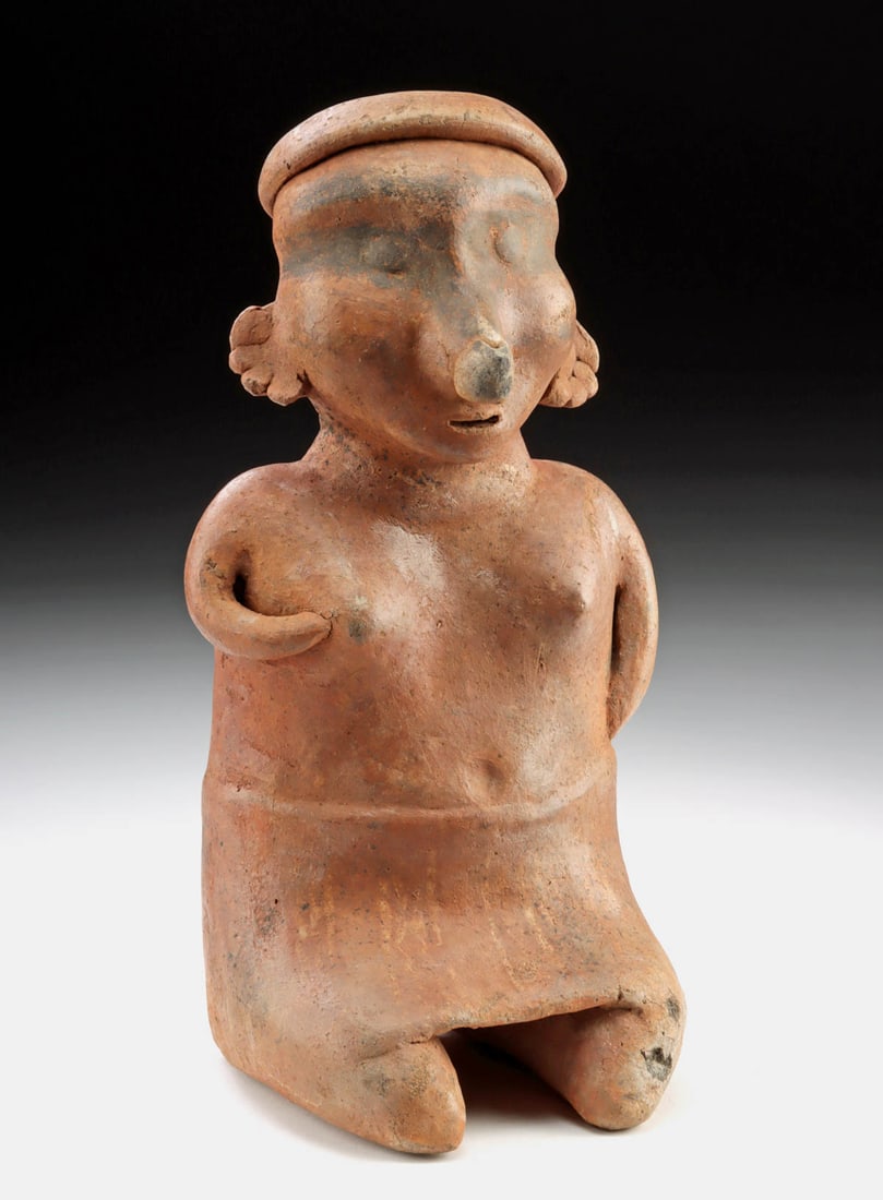 Nayarit Semi-Nude Seated Female Figure w/ Striped Skirt: Pre-Columbian, West Mexico, Nayarit, ca. 300 BCE to 300 CE. A quietly commanding terracotta figure, this seated woman embodies the earthy confidence and sculptural directness that define classic Nayar