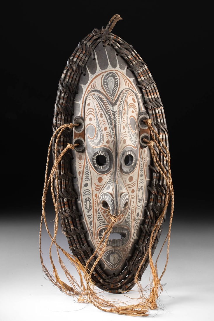 Sepik River Tambanum Wood Spirit Mask w/ Cane Rim: Oceania, Papua New Guinea, Middle Sepik River, Tambanum village, ca. 20th. A striking Sepik River spirit mask with elongated form and bold, graphic surface, framed by a woven cane rim and fiber attach