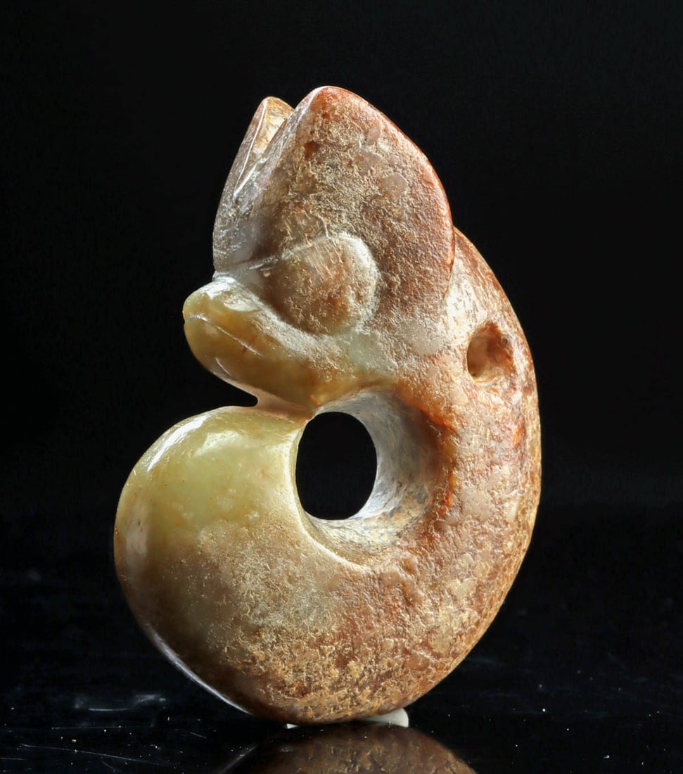 Chinese Hongshan Nephrite Jade Pig Dragon Pendant: China. Hongshan Culture, Neolithic Period, ca. 4700-2900 BCE. A carved nephrite jade pendant depicting a stylized pig-dragon (zhulong), formed as a thick, curled openwork arc with a pronounced head, r