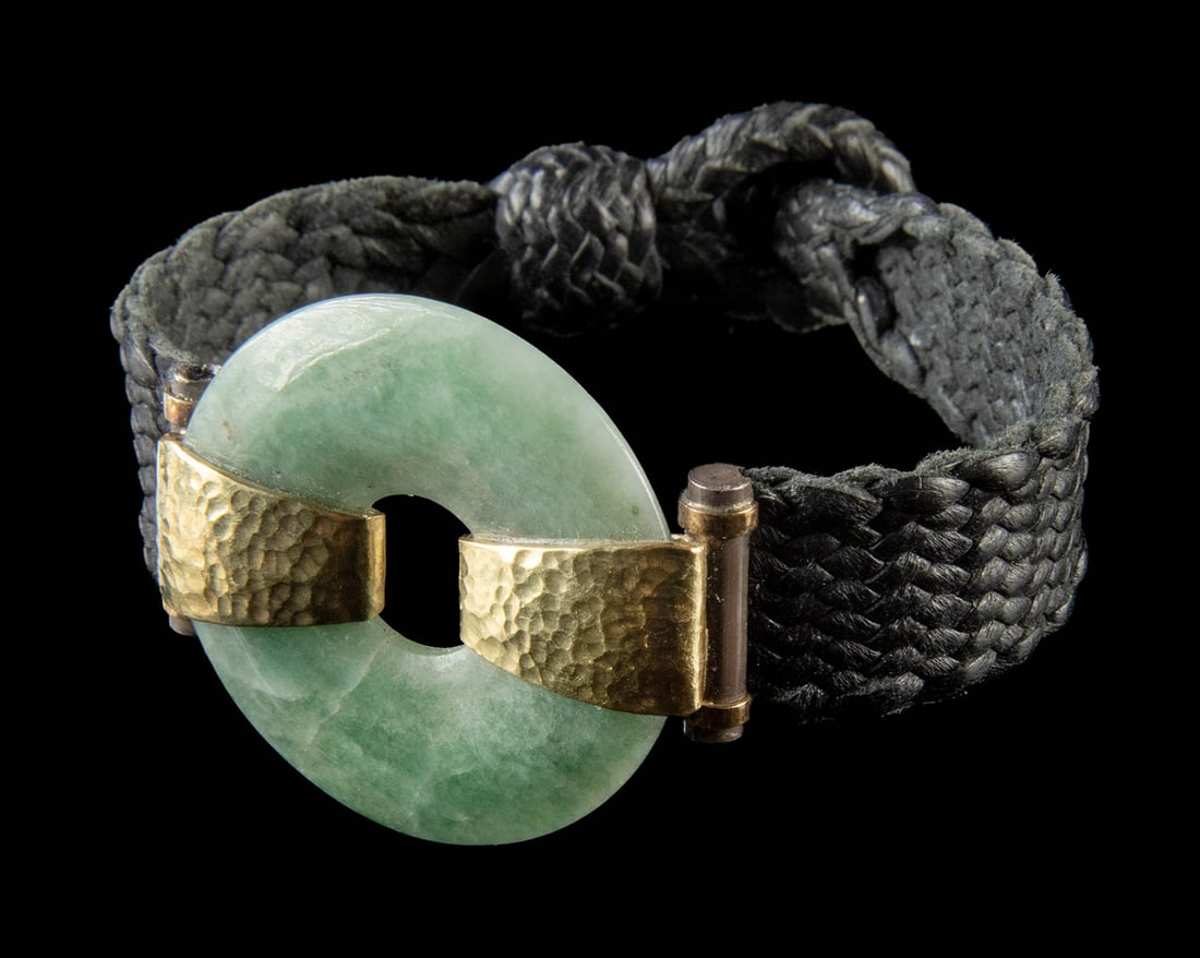 18K Gold & Stone 'Stefano' Bracelet by Consuelo Ulrich: Mexico, ca. 21st century CE. A leather band bracelet centered by a polished greenstone disc framed by two hammered 18K gold mounts. Part of the 'Stefano' line by Consuelo Ulrich, daughter of Alberto U
