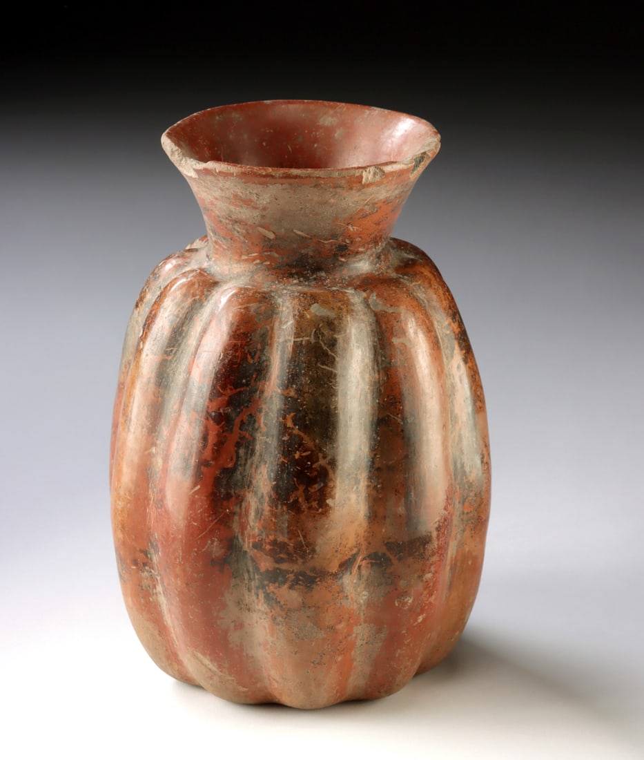 Colima Shaft Tomb Redware Vessel Gourd Effigy: Pre-Columbian, West Mexico, Colima, ca. 300 BCE to 300 CE. A redware pottery vessel formed in the lobed shape of a melon or gourd, with a flaring neck and softly modeled segments emphasizing its organ