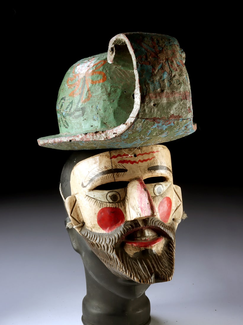 Vintage Mexican Guerrero Conquistador Mask w/ Helmet: Latin America, Mexico, Guerrero, ca. mid-20th century CE. A vividly painted face, crowned by a sweeping helmet and marked with a subtle cross upon the forehead, stares outward with theatrical authorit