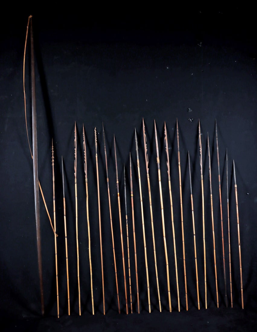 Papua New Guinea Dance & Warfare Wood Bow & Arrows: Oceania, Papua New Guinea, ca. early to mid-20th century CE. A carved wooden hunting and fishing bow accompanied by a group of wood and bamboo arrows, including a bowstring fashioned from split bamboo