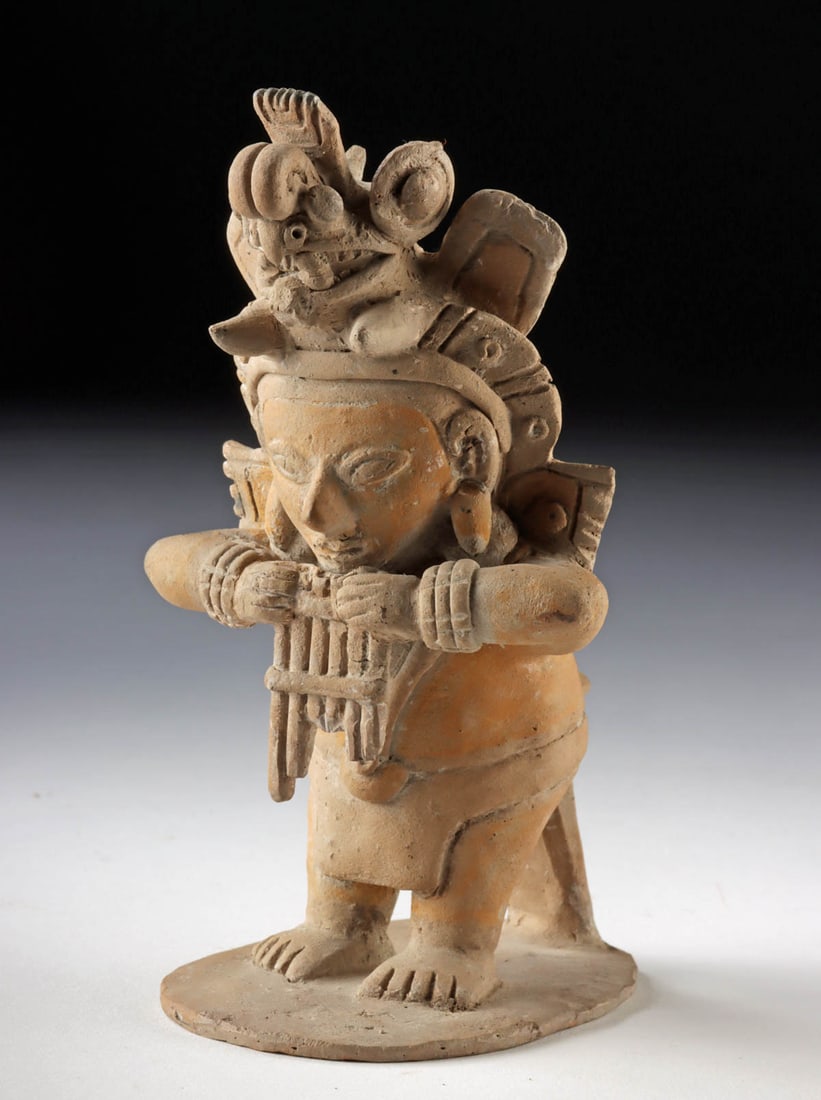 Jama-Coaque Terracotta Whistle - Panpipe Player: Pre-Columbian, Ecuador, Jama-Coaque culture, ca. 240 BCE to 450 CE. A lively terracotta musician playing a finely modeled panpipe (antara), crowned by an expressive zoomorphic headdress and, remarkabl