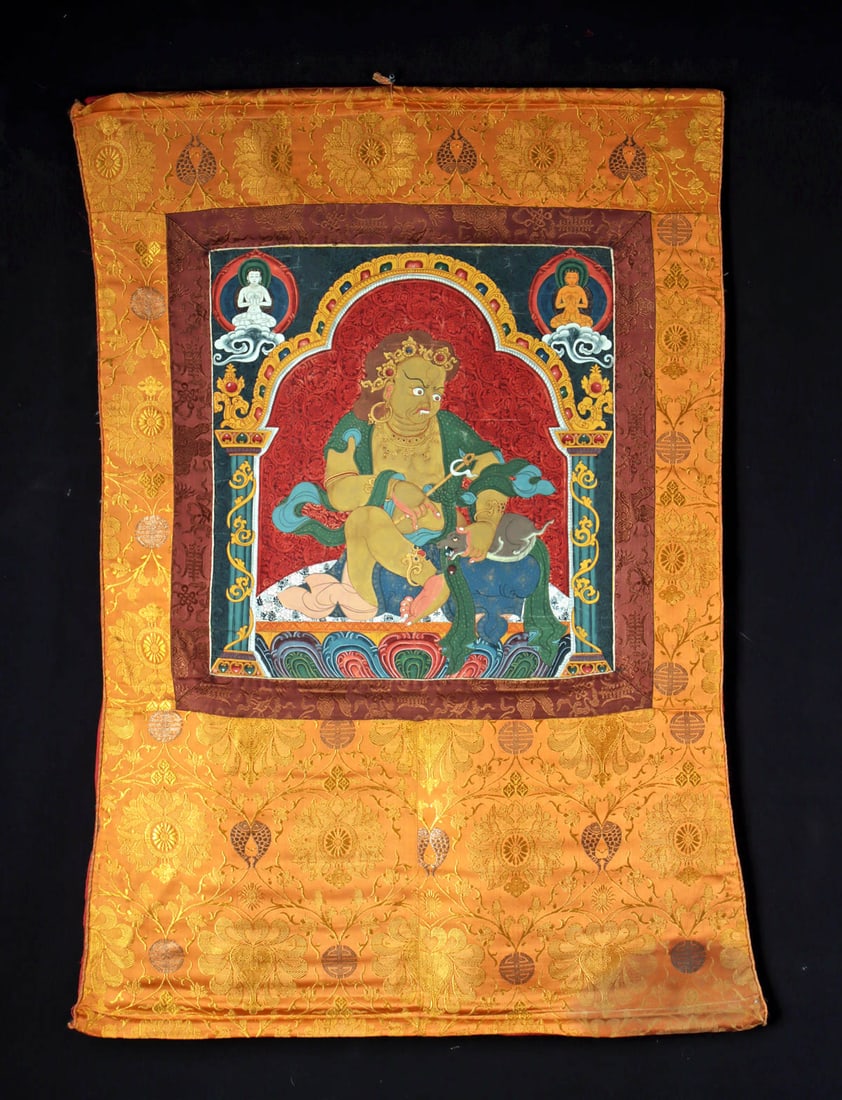Tibetan Gilt Thangka Silk Painting - Yellow Jambhala: Central Asia, Tibet, ca. early 20th century CE. A vivid thangka depicting Jijig, the frightful wealth deity better known as Yellow Jambhala, seated in a dynamic posture upon a lotus throne. His robust